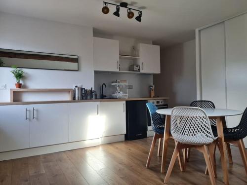 a kitchen with white cabinets and a table and chairs at Nid douillet proche des pistes avec vue montagne in Saint-Gervais-les-Bains