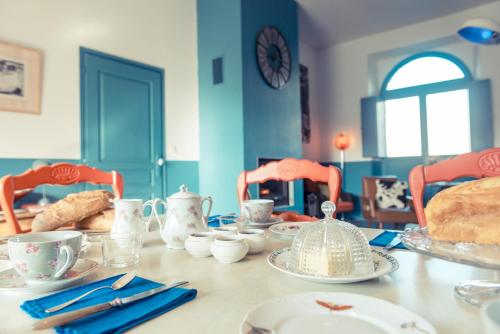 a table with plates and cups and bread on it at La Gare De Millas Chambres d'hôtes in Millas