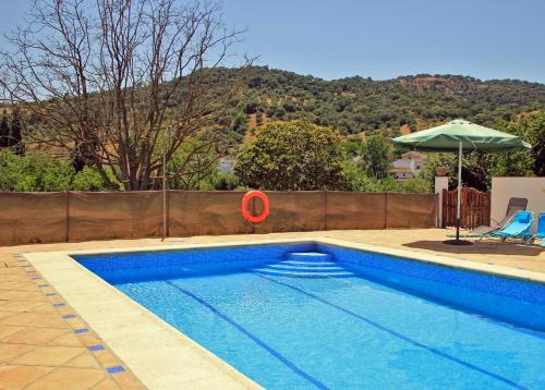 a blue swimming pool with an umbrella and an orange disk at Finca La Rana Verde in Cortes de la Frontera