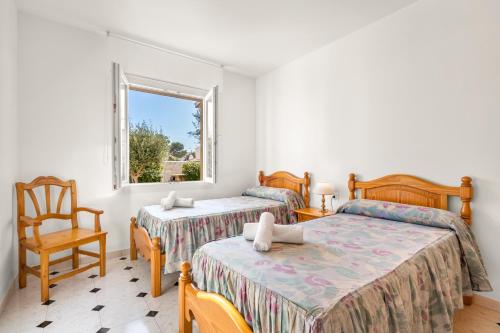 1 dormitorio con 2 camas, silla y ventana en Torres Sureda, en Cala Blanca