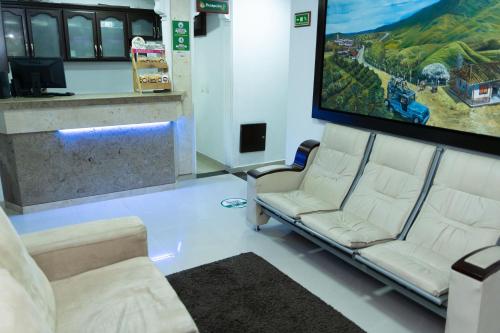 uma sala de espera com duas cadeiras brancas e um grande ecrã em Hotel Aires del Quindío Armenia em Armênia