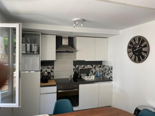 une cuisine avec des placards blancs et une horloge murale dans l'établissement Le Lavoir 1 /calme /Fibre /Bord de l'Yonne, à Auxerre