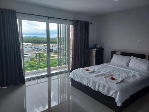 a bedroom with a bed and a large window at Thana Apartment in Ban Phan Sadet Nai