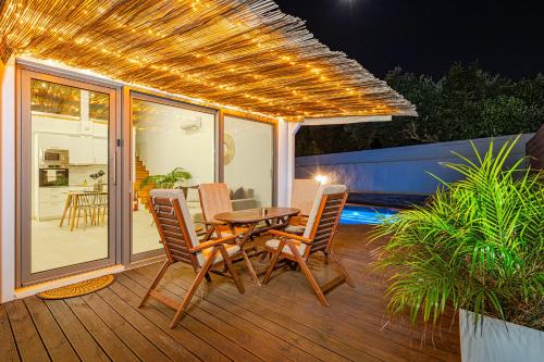 um pátio com uma mesa e cadeiras num deque em Cocoon Luxury Villas em Maleme