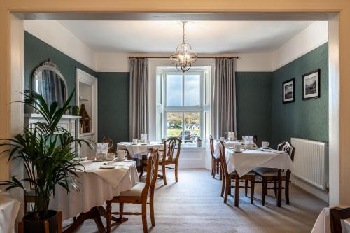 una sala da pranzo con tavoli e sedie e una finestra di Corriness House a Poolewe