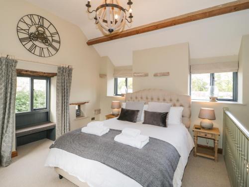 a bedroom with a large bed and a clock on the wall at The Dovecote in Denbigh