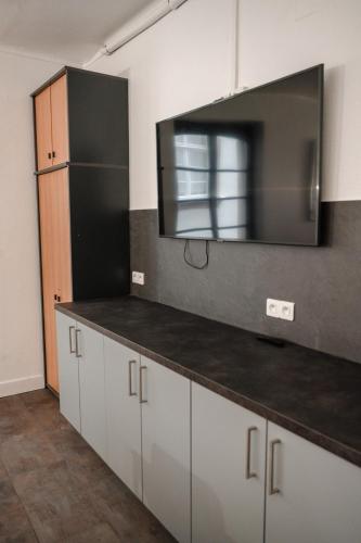 a kitchen with white cabinets and a television on the wall at Hotel des Arts - Centre Cathédrale in Strasbourg