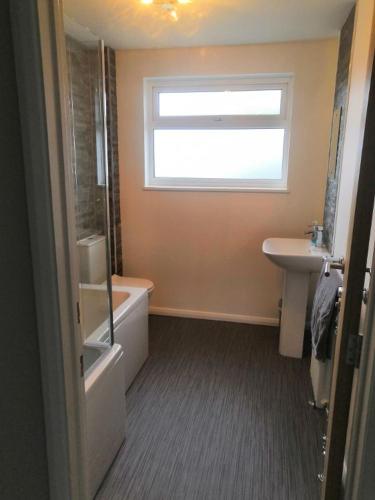 baño con bañera, lavabo y ventana en Number 49 en Great Torrington