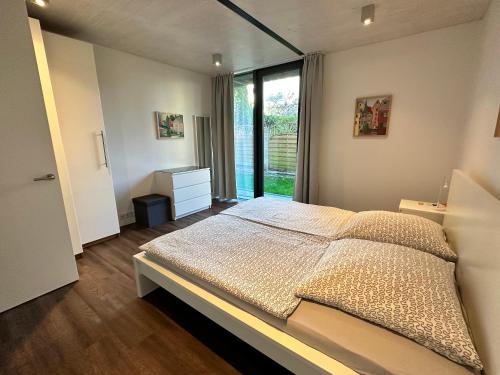 a bedroom with a bed and a large window at Ferienwohnung SEE UND MEHR in Stetten