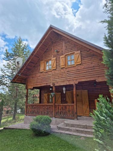 a large log cabin with a porch and windows at Rajska koliba in Kaludjerske Bare