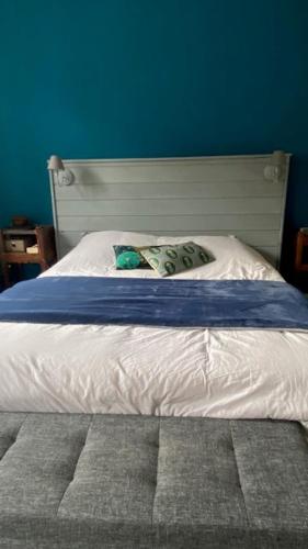- une chambre avec un lit blanc et un mur bleu dans l'établissement 23 Lesigne, à Lisieux