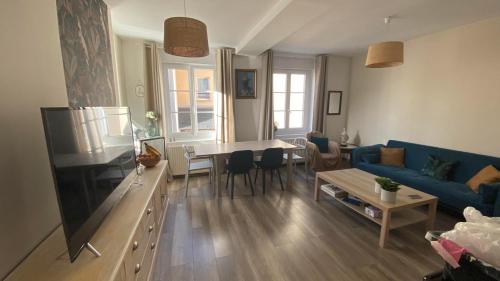 uma sala de estar com um sofá azul e uma mesa em 23 Lesigne em Lisieux