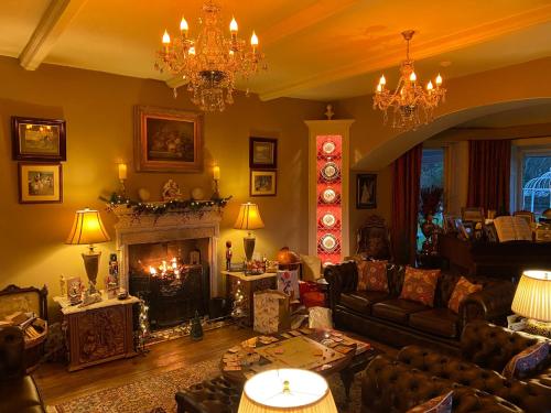 een woonkamer met een bank en een open haard bij Plas Tan-Yr-Allt Historic Country House & Estate in Porthmadog