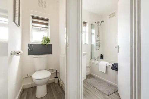 ein weißes Bad mit einem WC und einer Badewanne in der Unterkunft Luxury 3-Bed Apartment Near To London With Parking in Hornchurch