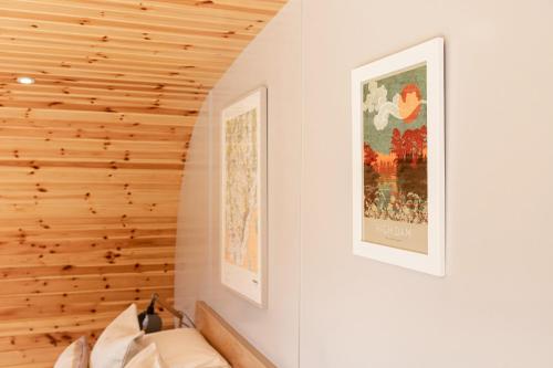 a bedroom with a wooden wall with two pictures on the wall at Little Heaning in Cartmel