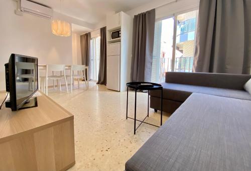 a living room with a couch and a television at Aptos La Costera in Benidorm