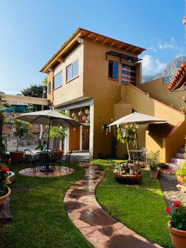 a house with an outdoor patio with tables and umbrellas at Ma Petite Maison in Tepoztlán