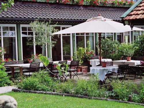 a patio with tables and chairs and an umbrella at Landhaus Benediktenhof in Bad Tölz