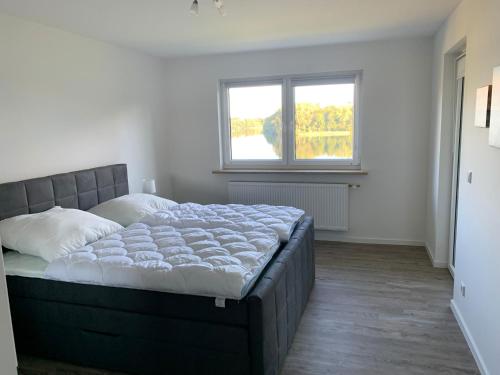 a bedroom with a large bed in a room with a window at Haus am See Wohnung 1 mit Studio in Stocksee