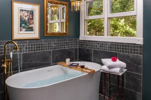 baño con bañera y 2 ventanas en Arsenic and Old Lace Bed & Breakfast Inn en Eureka Springs