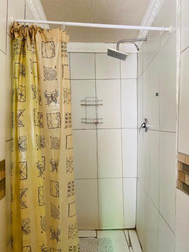 a shower with a yellow curtain in a bathroom at Village Stay Ngcamngeni in Debe Nek