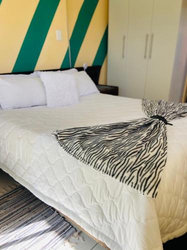 a bed with a black and white comforter on it at Village Stay Ngcamngeni in Debe Nek