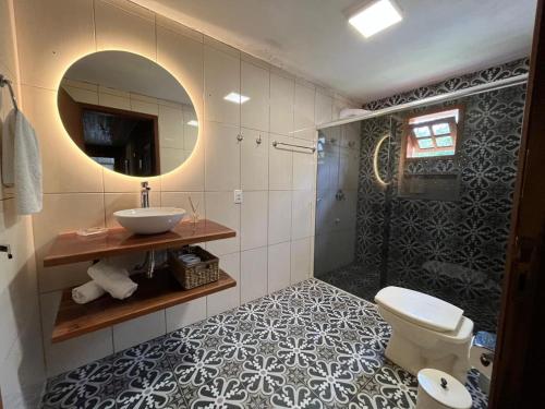 een badkamer met een wastafel, een toilet en een spiegel bij Pousada Costão da Serra in Lauro Müller