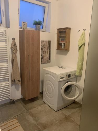 a laundry room with a washing machine and a window at Draußen am See in Losheim
