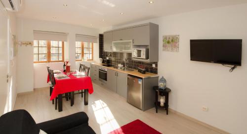 Apartments Porto Historico في بورتو: مطبخ وغرفة معيشة مع طاولة حمراء في غرفة