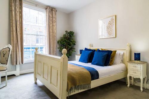 a bedroom with a bed with blue pillows and a window at Goodramgate Apartments in York
