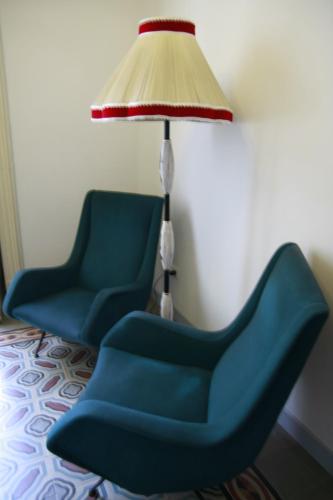 two blue chairs and a lamp in a room at Maison Decò in Catania
