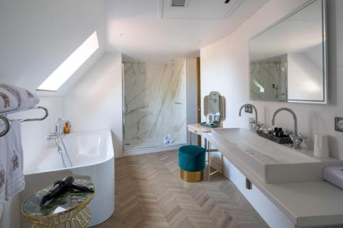 y baño blanco con bañera, lavamanos y bañera. en Hotel des Berges, Restaurant Gastronomique & Spa, en Illhaeusern