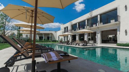 a pool with chairs and umbrellas next to a building at Casa en hermoso condominio, 10 personas! in San Miguel de Allende
