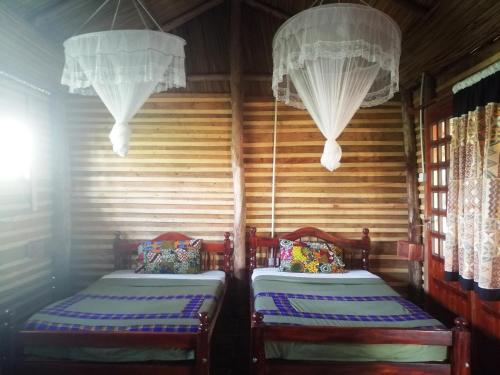 two beds in a room with curtains and chandeliers at Murchison Backpackers in Masindi