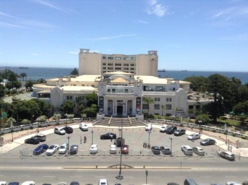 un gran edificio con coches estacionados en un estacionamiento en De la Barra, Arriendos Vista Mar, en Viña del Mar