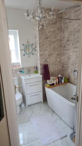 a bathroom with a tub and a toilet and a sink at Brightly lit double room is available in a home in Corby