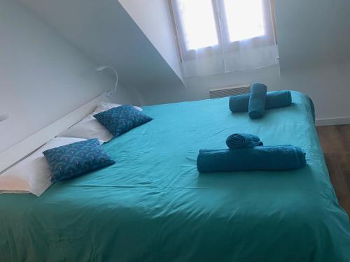 Una gran cama verde con almohadas azules. en Keryanne, en Saint-Gildas-de-Rhuys