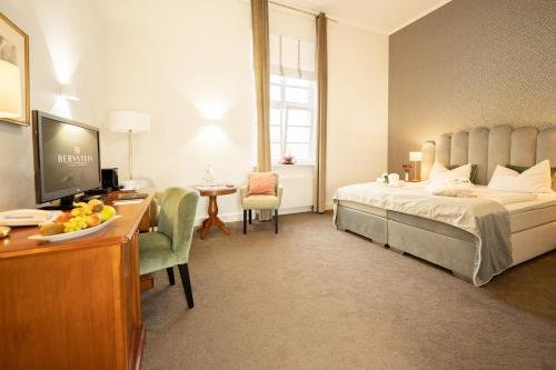 una camera d'albergo con letto e scrivania con computer di Bernstein Schlosshotel Ballenstedt a Ballenstedt