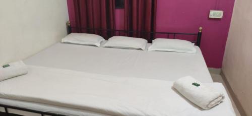 a white bed with two towels on top of it at Amit niwas in Mahabaleshwar