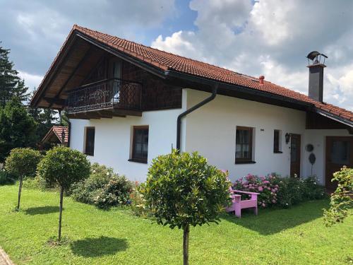 a white house with a pink bench in the yard at Seehäuschen - Waging Tettenhausen in Waging am See