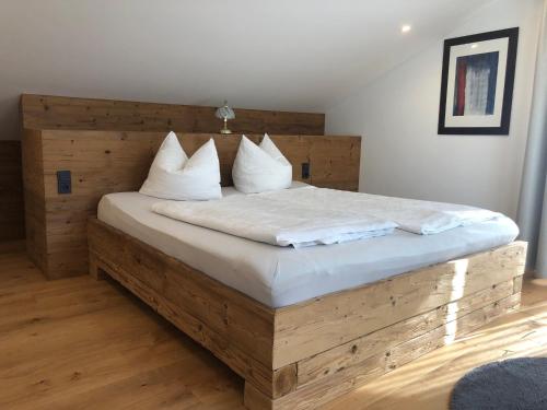 a bedroom with a wooden bed with white sheets and pillows at Seehäuschen - Waging Tettenhausen in Waging am See