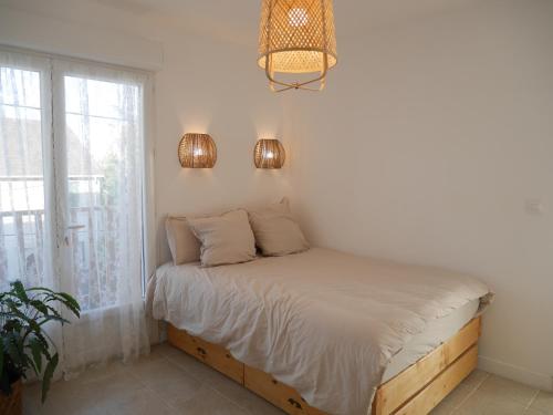 uma cama num quarto com uma janela e duas luzes em La maison aux bambous em Montreuil