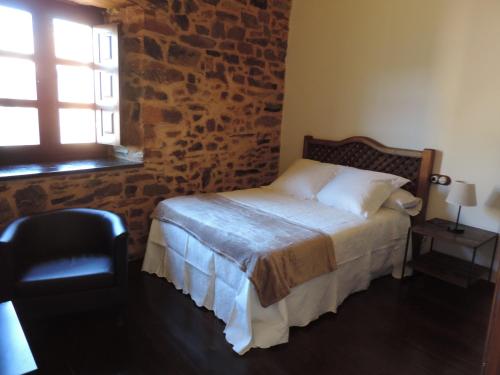 sypialnia z łóżkiem i ceglaną ścianą w obiekcie El Rincón Maragato w mieście Castrillo De Los Polvazares