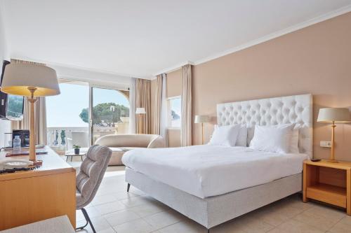 a bedroom with a large white bed and a living room at Van der Valk Hotel Barcarola in Sant Feliu de Guíxols