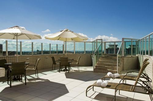 eine Terrasse mit Tischen, Stühlen und Sonnenschirmen in der Unterkunft Pampulha Lieu Hotel in Belo Horizonte