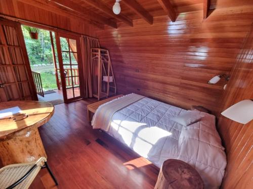 1 dormitorio con 1 cama en una habitación de madera en Oxablues Home Lodge, en Oxapampa