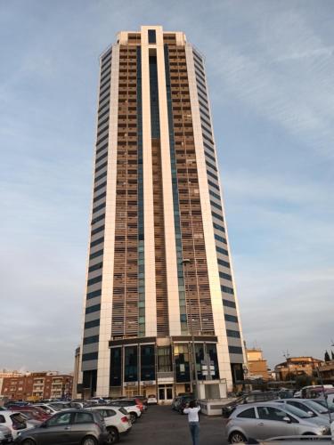 a tall building with cars parked in a parking lot at La torre in Latina
