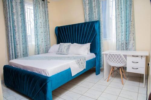 a bed with a blue headboard in a bedroom at Royal Haven A3 Spacious 1Br Apartment 10min drive to beach hosts upto 4 guests WiFi - Netflix, 10min drive to beach in Mombasa