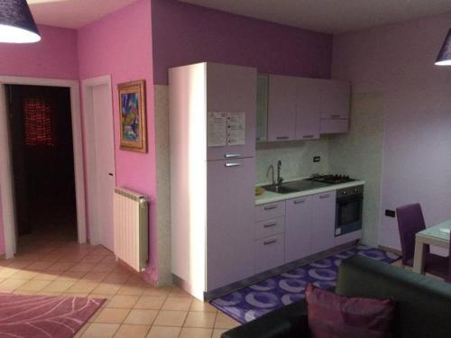 a kitchen with pink walls and white cabinets at Enea residence in Pozzuoli