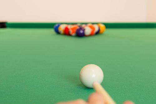 a person playing billiard with a cue on a pool table at Chiemgauferienwohnungen - Maier in Unterwössen